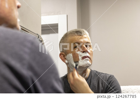 Reflection in the mirror of the man shaving 124267785