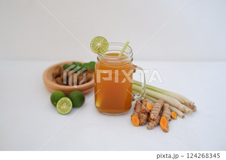 Fresh ginger and lemon juice in a glass jar with ginger roots on white background. Fresh ginger and lemon juice in a glass jar with ginger roots on white background. 124268345