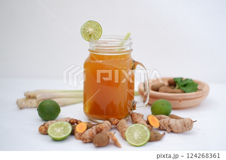 Fresh ginger and lemon juice in a glass jar with ginger roots on white background. Fresh ginger and lemon juice in a glass jar with ginger roots on white background. 124268361