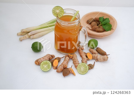 Fresh ginger and lemon juice in a glass jar with ginger roots on white background. Fresh ginger and lemon juice in a glass jar with ginger roots on white background. 124268363