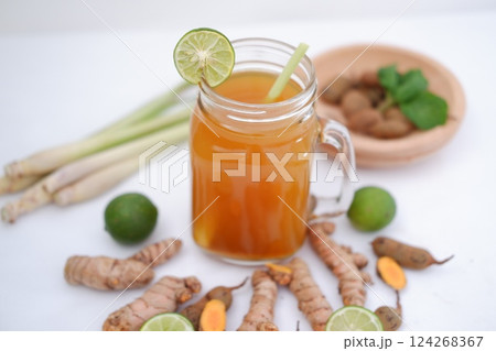 Fresh ginger and lemon juice in a glass jar with ginger roots on white background. 124268367
