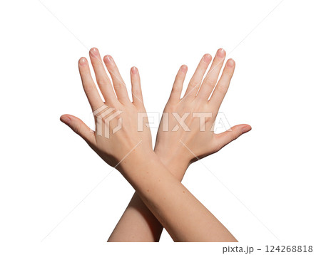 Well-groomed female hands with glossy, polished nails crossing at the wrist. Neat, soft skin with a 124268818
