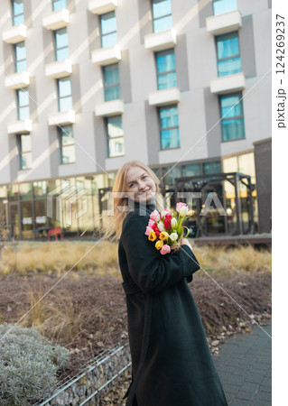 Happy International Women's Day Concept. Beautiful happy Caucasian woman smelling bunch of tulips with closed eyes Happy International Women's Day Concept. Beautiful happy Caucasian woman smelling bunch of tulips with closed eyes 124269237