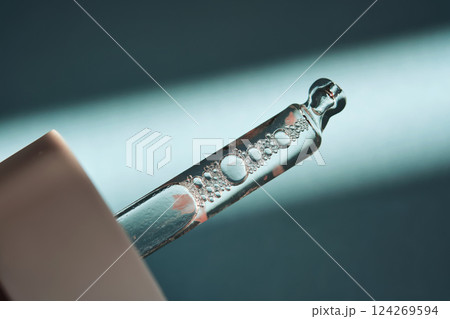 Pipette with serum on blue background with sunlight. 124269594