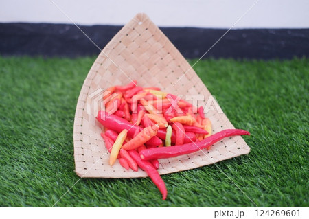 Red and yellow chilli in rattan basket on green grass Red and yellow chilli in rattan basket on green grass 124269601
