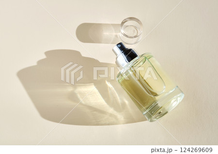 Perfume on a beige background in the rays of bright sun with beautiful highlights. 124269609