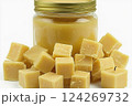 Yellow, pure beeswax is displayed in a glass jar alongside neatly cut cubes. They can be used for various crafting activities, including candle making and skincare Generative AI 124269732