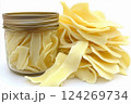 Dried mango slices are arranged artfully around a glass jar filled with the same dried fruit. Their light color and smooth texture highlight their natural sweetness Generative AI 124269734