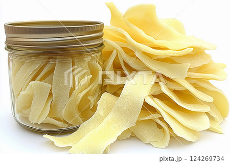Dried mango slices are arranged artfully around a glass jar filled with the same dried fruit. Their light color and smooth texture highlight their natural sweetness Generative AI 124269734