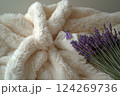 A soft, fluffy blanket serves as a backdrop for a small decorative pillow and a fragrant bundle of lavender, creating a peaceful indoor setting Generative AI 124269736