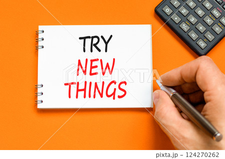 Try new things symbol. Concept words Try new things on beautiful white note. Beautiful orange background. Businessman hand. Business motivational lifestyle try new things concept. Copy space. 124270262