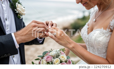 A man is carefully placing a wedding ring onto a womans finger 124270912