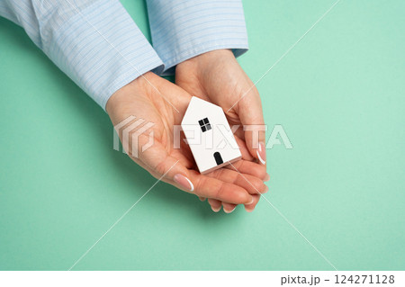A figurine of a house in the palms of a woman. Dreaming of your own home. Homeownership. Achieving stability, building equity, and creating a safe space for family memories and milestones. 124271128