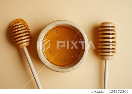 Wooden honey dipper and bowl of pure golden honey on neutral background 124272802