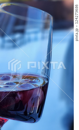 Female hand with glass of red wine against backdrop of nature. Vertical photo. High quality photo 124273686