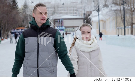 Romantic couple gliding together, holding hands on frosty ice rink surrounded by snow covered urban park landscape Romantic couple gliding together, holding hands on frosty ice rink surrounded by snow covered urban park landscape 124274008