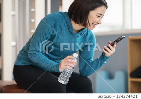 スポーツジムでスマホを見る女性 124274421