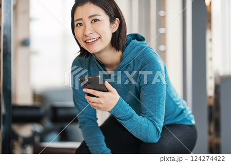 スポーツジムでスマホを持つ女性 124274422