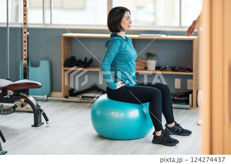 スポーツジムに通いバランスボールで体幹を鍛える女性 124274437