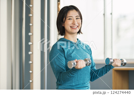 スポーツジムで鉄アレイを使って筋トレをする女性 スポーツジムで鉄アレイを使って筋トレをする女性 124274440