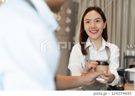 Sustainability and Customer Engagement. A barista engages with customers while promoting reusable cups. 124274695