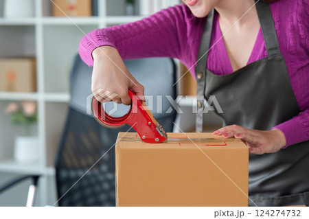 Sealing Packages for Shipment. An online seller using tape to secure a box. 124274732