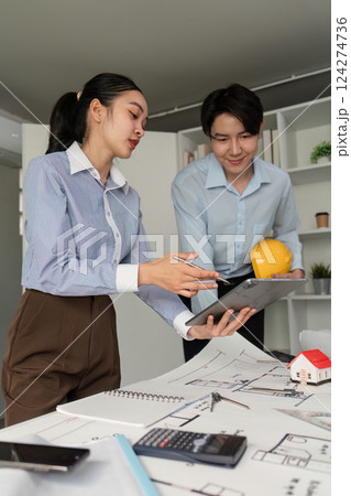 Strategic Planning and Teamwork. A professional collaborating with a colleague on architectural plans with a tablet. 124274736