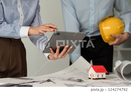 Collaboration and Construction Planning. Professionals discussing architectural plans while using a tablet for project management. 124274792