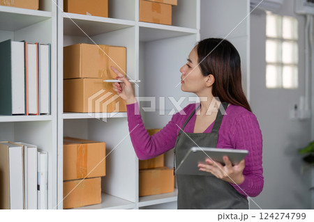 E-commerce and Stock Organization. A woman checking inventory levels while preparing for online sales in a tidy warehouse. 124274799