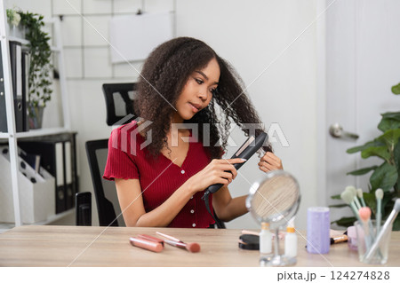 Natural Beauty and Self-Care. A woman styles her hair while enjoying a moment of self-expression. 124274828