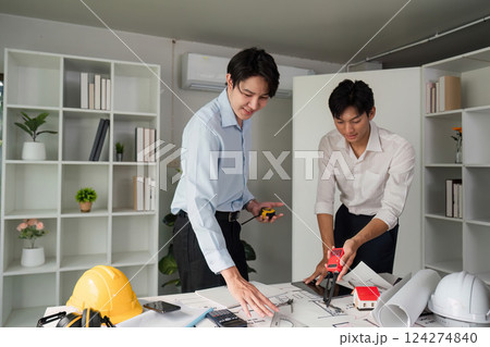 Building Plans and Collaboration. Two professionals analyzing architectural plans and discussing measurements. Building Plans and Collaboration. Two professionals analyzing architectural plans and discussing measurements. 124274840