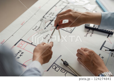 Collaboration and Precision. Close-up of professionals working together on architectural plans with compasses and rulers. Collaboration and Precision. Close-up of professionals working together on architectural plans with compasses and rulers. 124274841