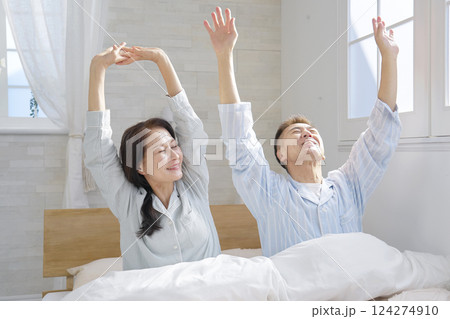 ベットで伸びをする夫婦　朝 124274910