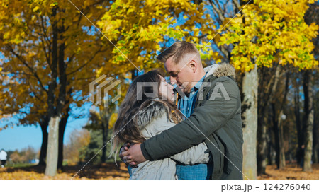 Loving couple hugging among golden leaved trees during bright autumn afternoon Loving couple hugging among golden leaved trees during bright autumn afternoon 124276040