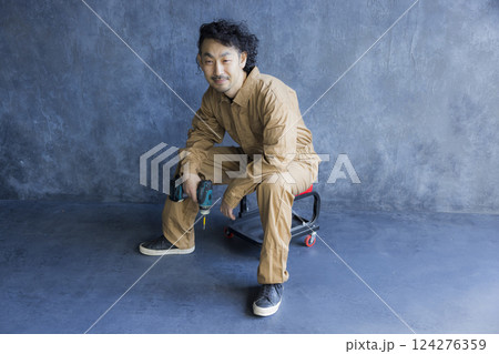 作業椅子に座るつなぎの男性 作業椅子に座るつなぎの男性 124276359