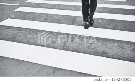 Young woman walking across street, black denim pants and leather boots during fall season 124276506