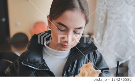 Woman enjoying fresh flatbread, relaxing in warm cafe, embodying culinary comfort and serene personal dining experience 124276586