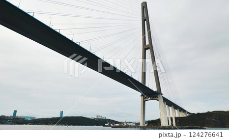 Modern cable stayed bridge dominating seascape, connecting landmasses under a cloudy sky, showcasing strength and elegance in infrastructure design 124276641