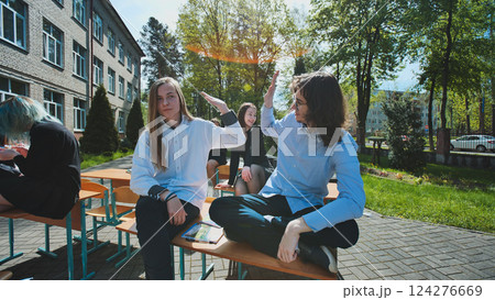 High school students celebrating friendship and academic success with high fives outdoors on a sunny school day High school students celebrating friendship and academic success with high fives outdoors on a sunny school day 124276669
