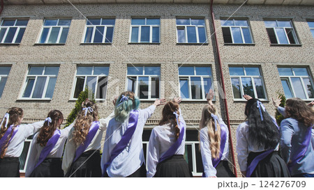 Group of graduating students waving goodbye to their school building on their last day, celebrating the end of an era 124276709