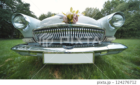 Vintage volga sedan adorned with blossoms, resting on verdant lawn during wedding preparations Vintage volga sedan adorned with blossoms, resting on verdant lawn during wedding preparations 124276712