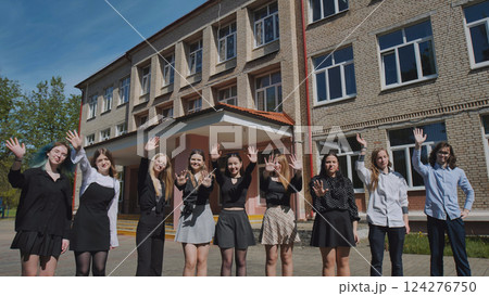 Happy students bid farewell outside their high school building on a beautiful, sunny day 124276750