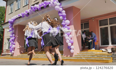 Excited graduates running out of school on last day, celebrating freedom under purple balloons. Childhood ends, new chapter begins. Sunny day, carefree fun with friends Excited graduates running out of school on last day, celebrating freedom under purple balloons. Childhood ends, new chapter begins. Sunny day, carefree fun with friends 124276820