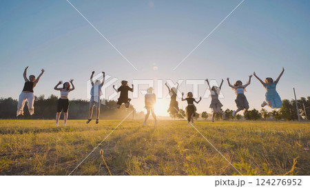 Group of joyful high school students jumping with raised arms in a field at sunset, celebrating summer holidays Group of joyful high school students jumping with raised arms in a field at sunset, celebrating summer holidays 124276952
