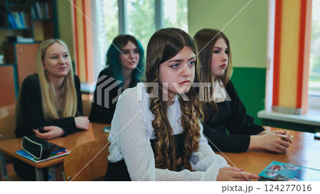 Focused high school female students engaged in classroom lesson with teacher Focused high school female students engaged in classroom lesson with teacher 124277016