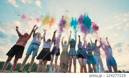 School friends joyfully tossing colorful powder in the air at sunset, commemorating their friendship and making lively memories 124277229