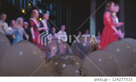 Jubilant graduates standing on stage, embracing amid vibrant balloons, marking academic milestone with shared excitement and pride Jubilant graduates standing on stage, embracing amid vibrant balloons, marking academic milestone with shared excitement and pride 124277315