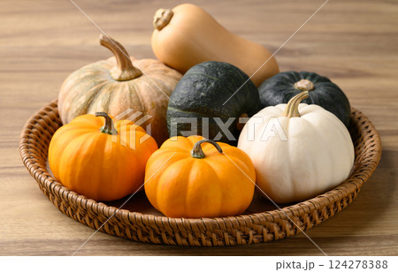 Various pumpkins in basket on wooden background 124278388