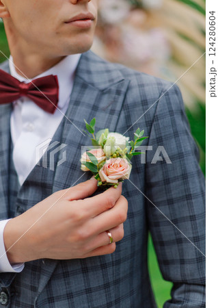 A young groom adjusts the boutonniere on his A young groom adjusts the boutonniere on his 124280604