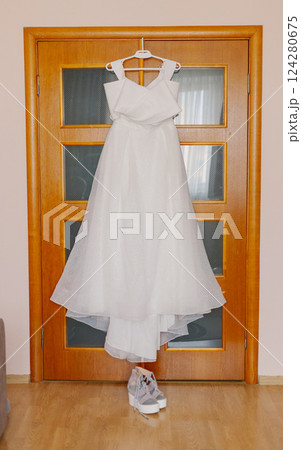 A beautiful white wedding dress hangs on a wooden 124280675